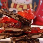 close up image of black forest chocolate candy bark on a white plate with a candy tin in the background