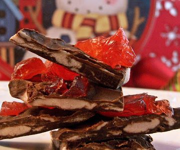 close up image of black forest chocolate candy bark on a white plate with a candy tin in the background