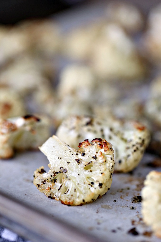 close up image of roasted cauliflower on a cookie sheet lined with parchment