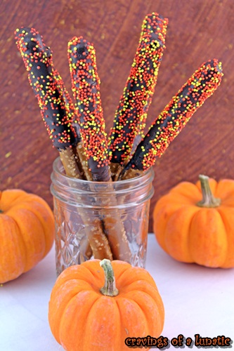 pretzels dipped in chocolate and sprinkles and stashed in a mason jar surrounded by mini pumpkins