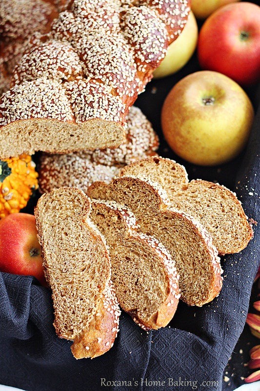 Whole Wheat Pumpkin Challah served in a towel lined bread basket with apples and mini pumpkins