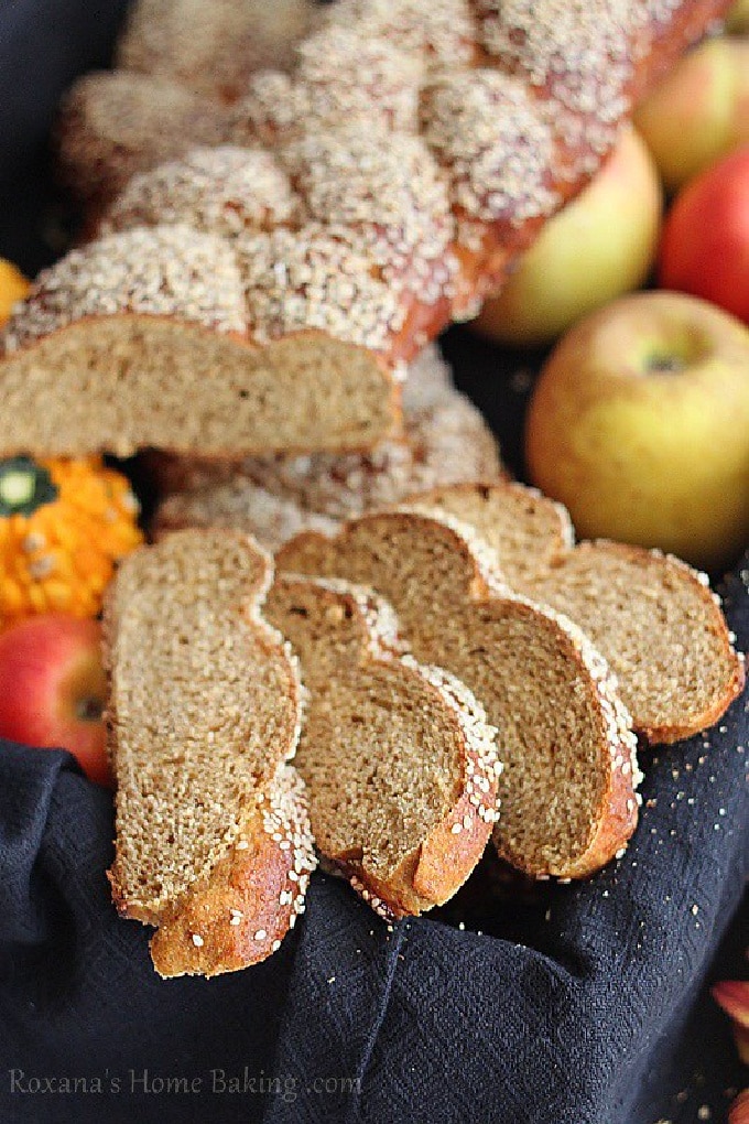 Whole Wheat Pumpkin Challah served in a towel lined basket with apples and mini pumpkins