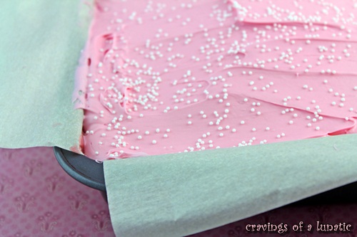 Strawberry Krispies with Pink Frosting in pan with parchment paper lining it