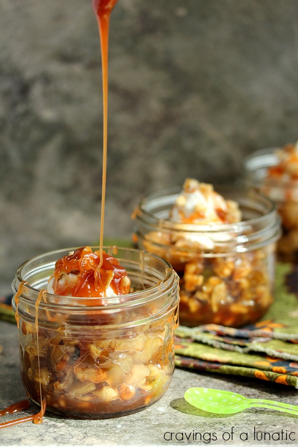 Fried Apples with Apple Caramel Sauce served in small wide mouth mason jars with extra caramel being poured over top