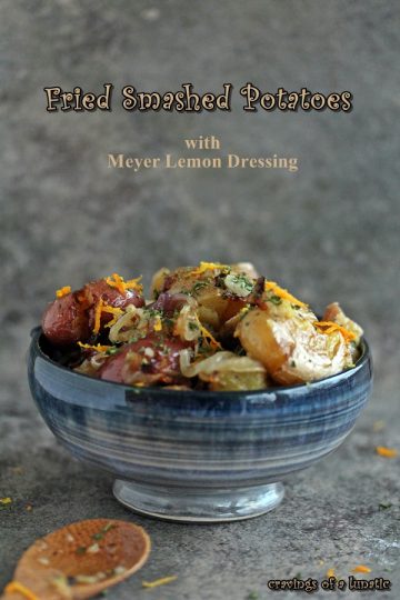 Fried Smashed Potatoes with Meyer Lemon Dressing in a blue bowl on a counter