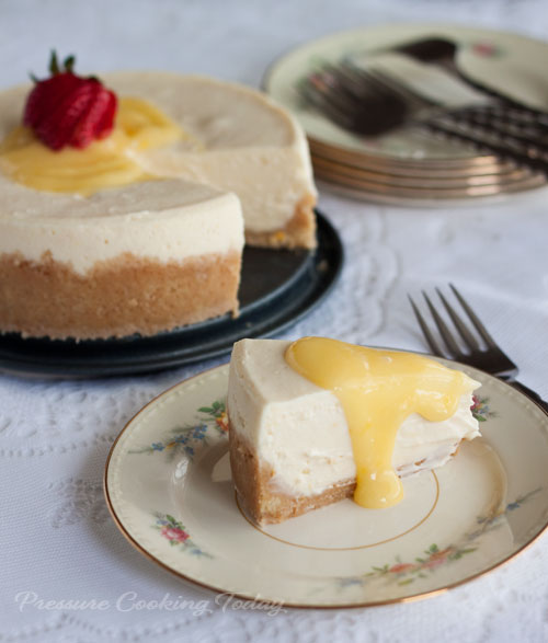 Meyer Lemon Cheesecake slice on plate with large cake in background. 