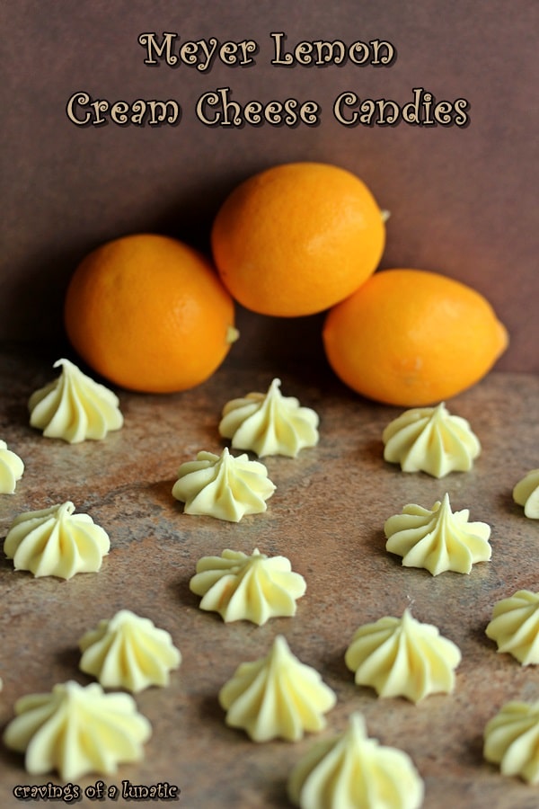 Meyer Lemon Cream Cheese Candies on a wood board with lemons in background. 
