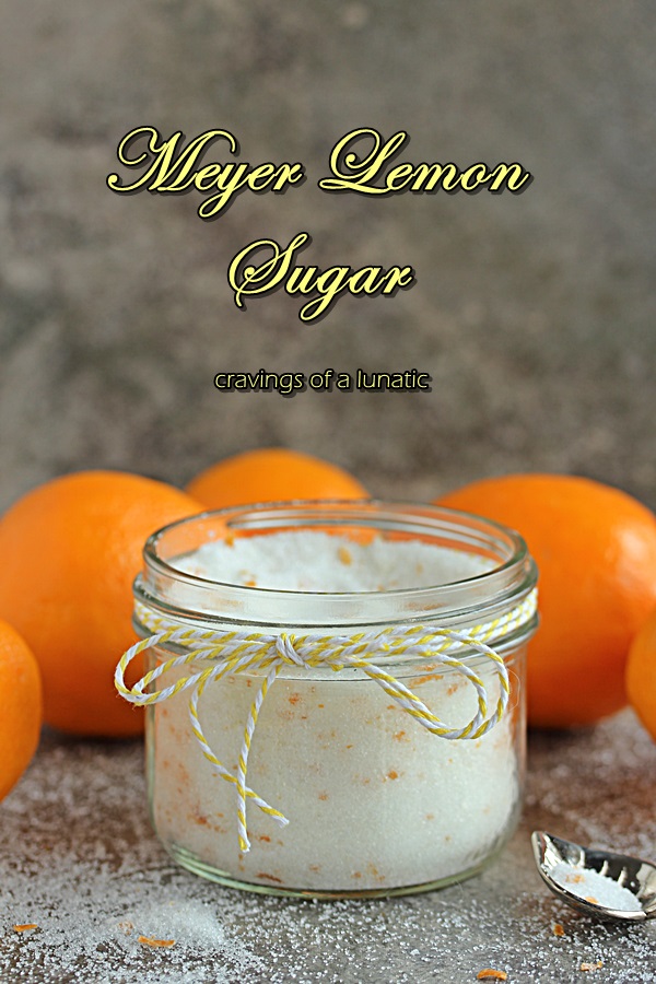 meyer lemon sugar stored in a mason jar, spoon resting on counter and meyer lemons are in the background
