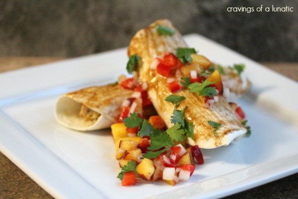 asian inspired enchiladas with chicken, quinoa and peach salsa piled on a white plate and topped with peach salsa