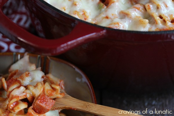 close up image of pizza pasta in red dutch oven with a spoonful of pasta scooped out