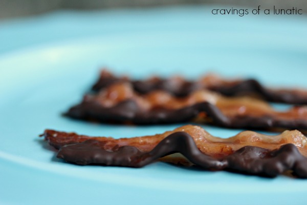 strips of Chocolate Covered Candied Bacon on a blue plate