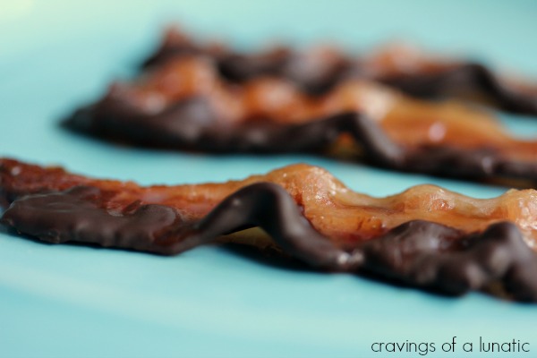 3 strips of chocolate covered candied bacon on a blue plate