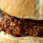 Slow Cooker Root Beer Pulled Pork close up image of sandwich on a white plate