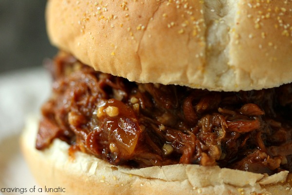 Slow Cooker Root Beer Pulled Pork close up image of sandwich on a white plate