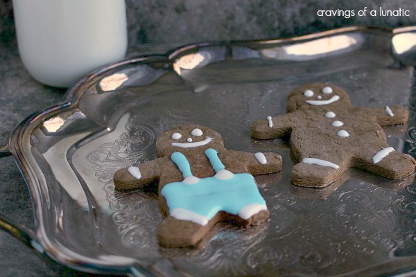 gingerbread people on a metal tray with a glass of milk behind it