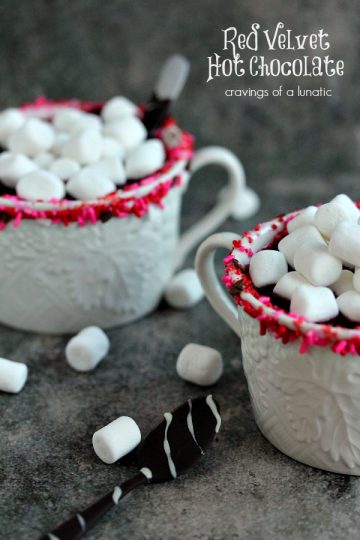 Red Velvet Hot Chocolate served in white mugs with chocolate covered spoons on the counter.