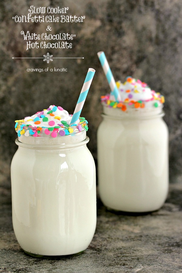 Slow cooker white chocolate hot chocolate served in mason jars with sprinkles on the rim and straws inside the glasses. 