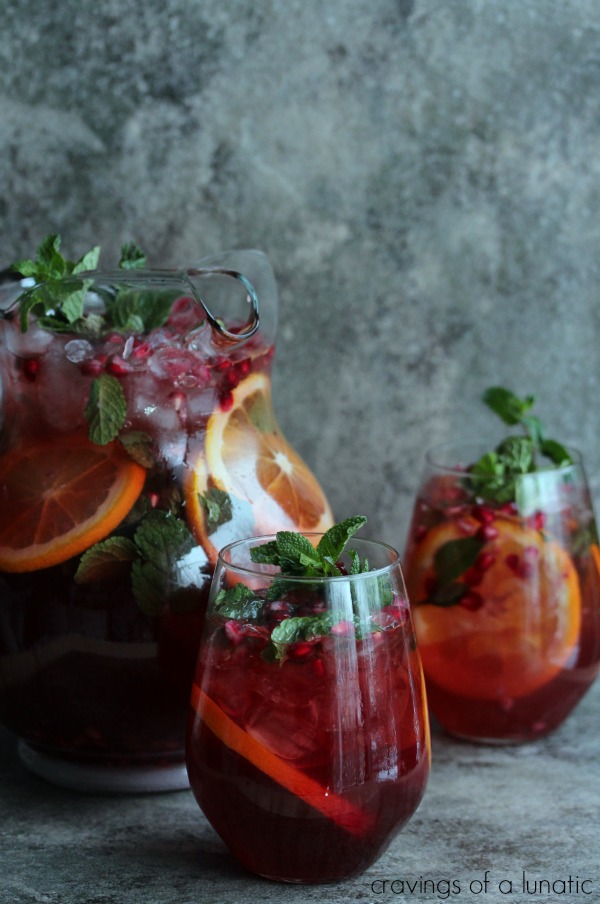 Pomegranate Party Punch in a glass pitcher and wine tumblers