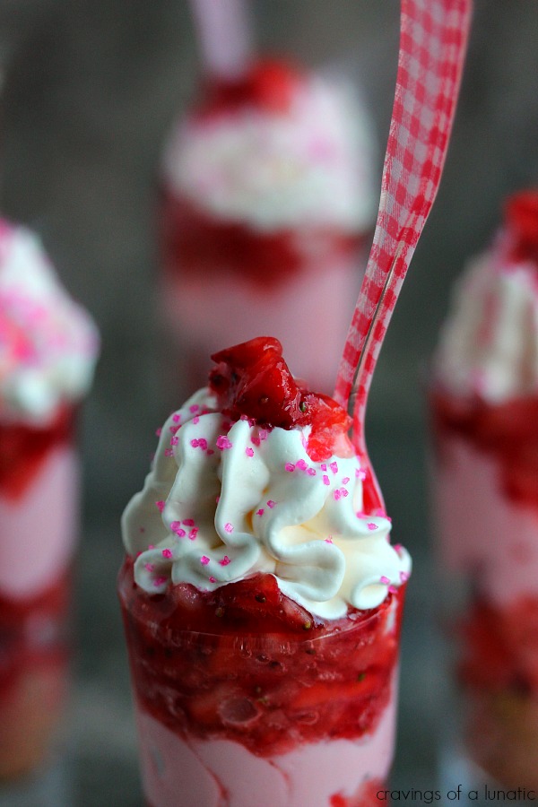 close up image of Strawberry Shortcake No Bake Mini Cheesecakes served layered in tall shot glasses with brightly colored spoons