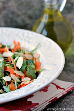 Arugula Salad with Shaved Carrots, Shaved Asparagus and Almonds served in a white bowl.
