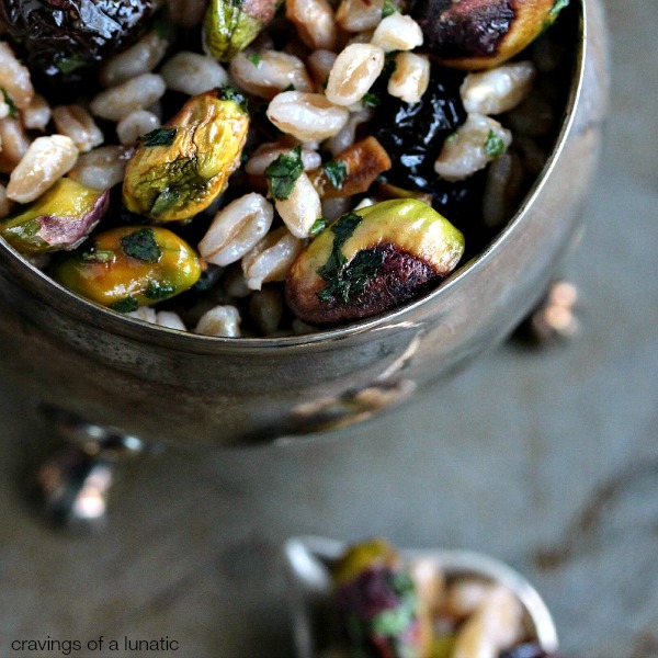 Farro with Pistachios and Dried Cherries served in a silver bowl on a dark counter.