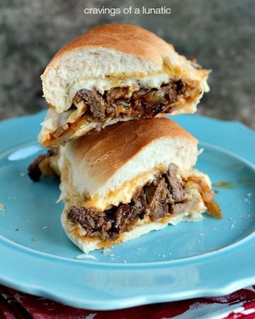 Steak Sandwiches cut in half and piled on a blue plate.