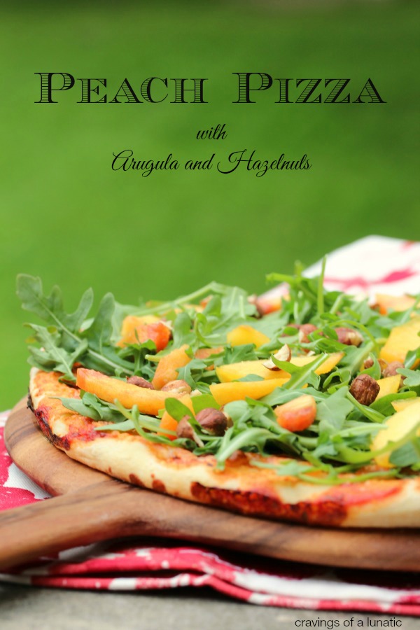 Pizza with Arugula, Peaches and Hazelnuts on a wooden board