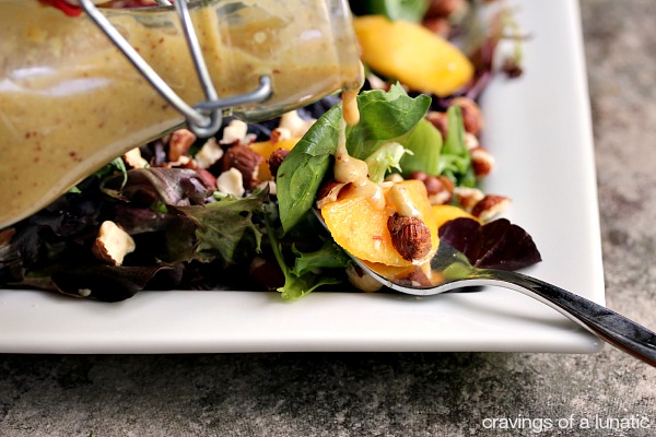 Peach Salad on a white plate with Peach and Hazelnut Dressing being poured over top