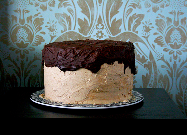 B52 Layer Cake on a plate with lots of chocolate ganache on top of the cake