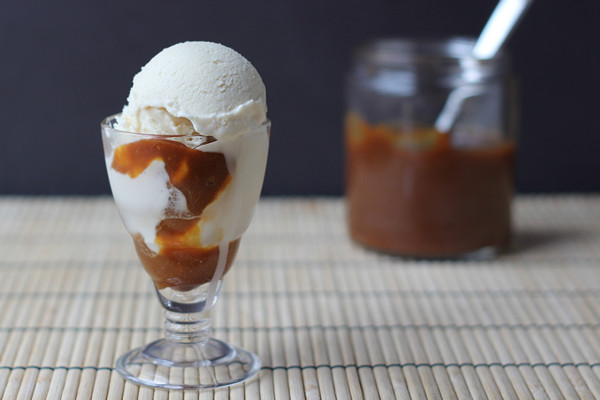 Baileys Ice Cream Sundae in a tall glass dish with a jar of caramel sauce in the background. 