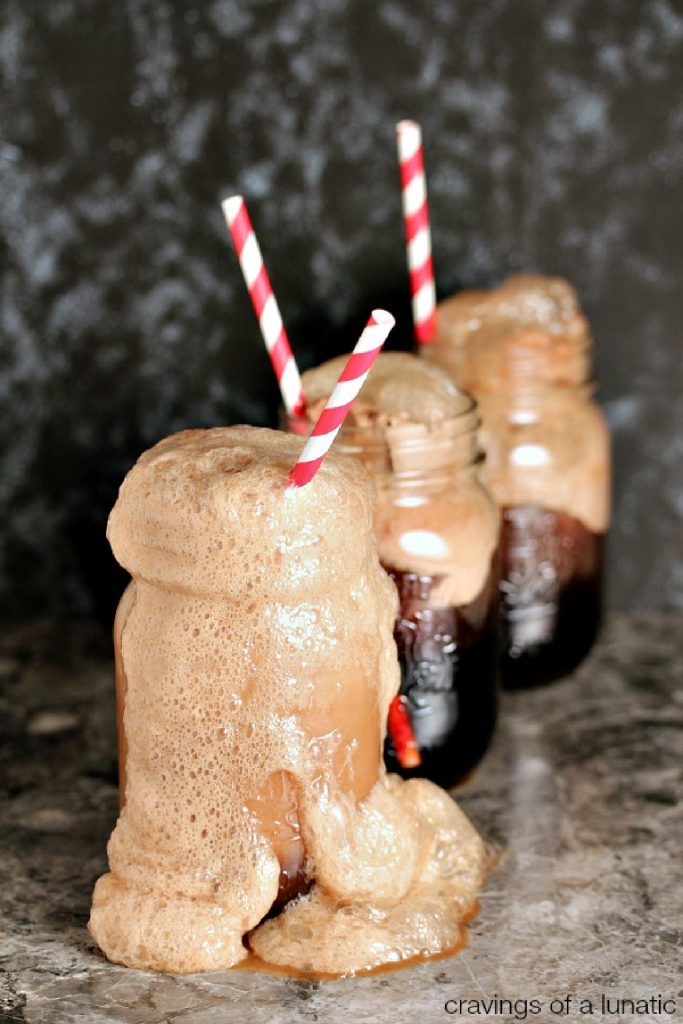 Three mason jars filled with cherry cola floats with straws in them on a counter. 