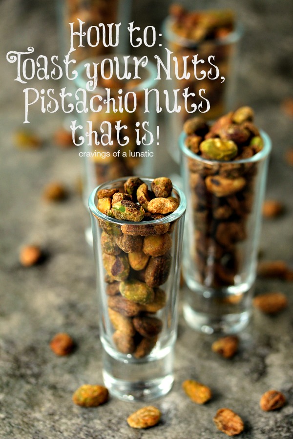 Toasted nuts in shot glasses on a dark surface with pistachios scattered around.