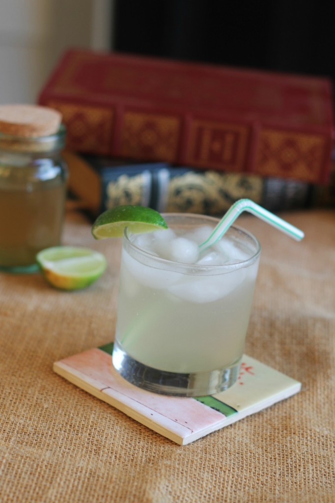 Light Drizzle cocktail on a coaster with ingredients and books in the background. 