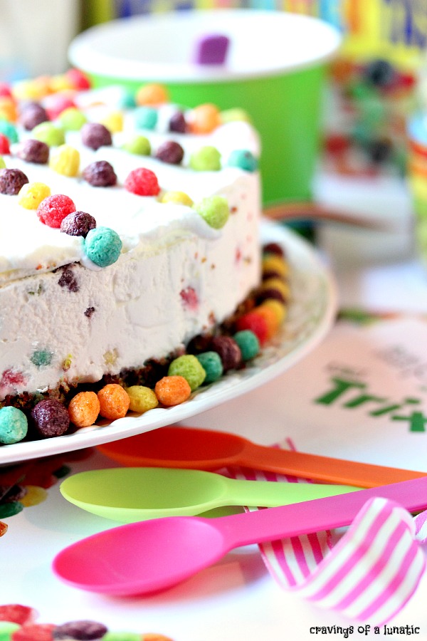 Trix Ice Cream Cake served on a white platter with lots of colourful spoons and cups nearby