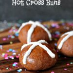 Chocolate Hot Cross Buns on a wood board with confetti all around.