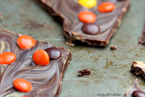 Peanut Butter and Chocolate Bark with Reese's Pieces broken into pieces on a cookie sheet.