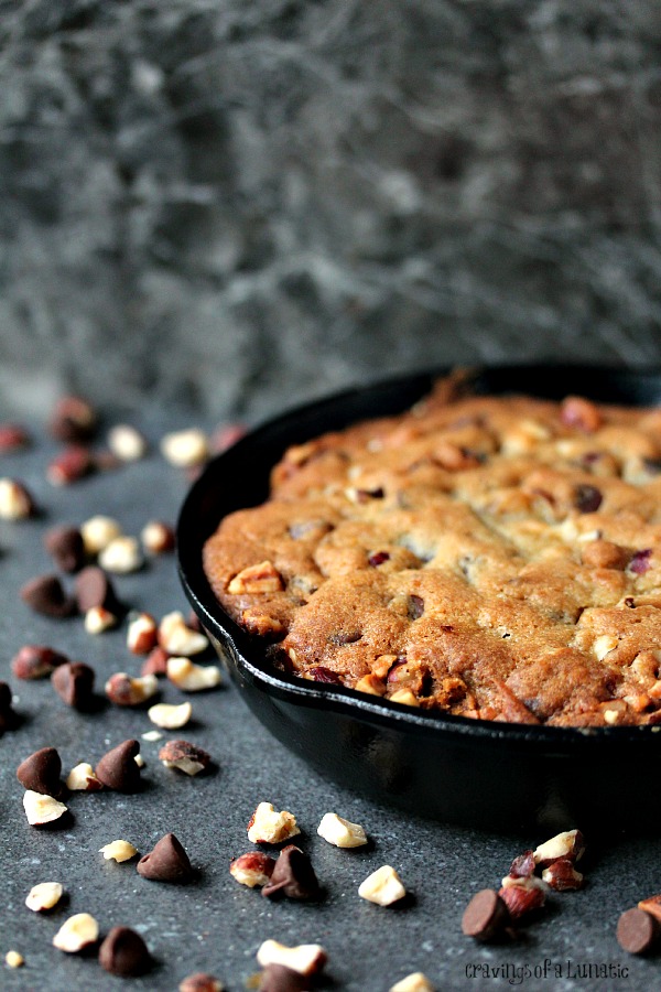 Chocolate Hazelnut Skillet Cookie on a dark counter with ingredients spilled all over it.