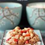 Creamy Cashew Chicken serve over rice on a blue plate with blue bowls in the background