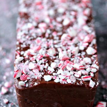 Easy Chocolate Peppermint Fudge on a grey counter with crushed peppermint scattered about.