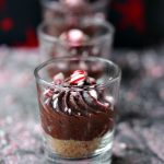No Bake Chocolate Peppermint Cheesecakes served in shot glasses with crushed peppermints scattered on top of the dessert.