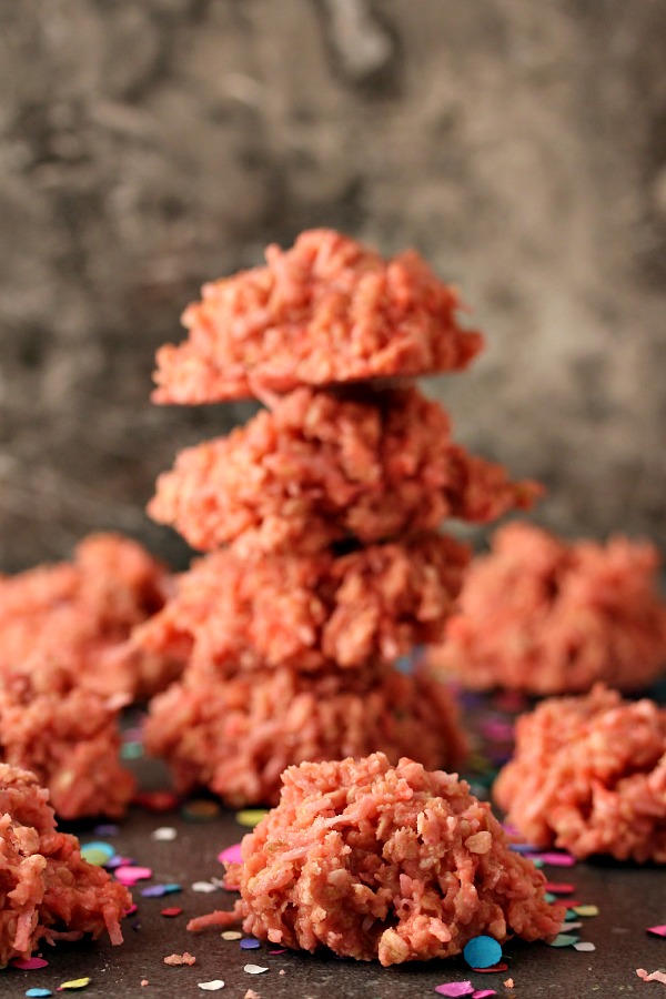 Pink Coconut Cookies stacked and randomly places on a dark counter.