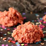 Pink Coconut Cookies on a dark surface with brightly coloured confetti sprinkled around.