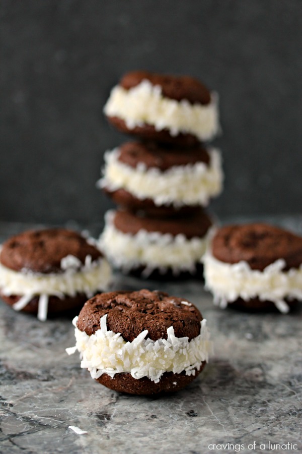 Coconut Filled Sandwich Cookies stacked and scattered on a grey marble counter.