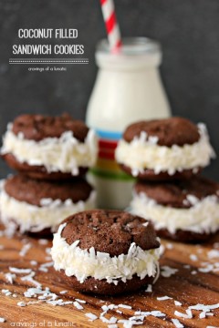 Coconut Filled Sandwich Cookies on a wood board with a small bottle of milk in the background.