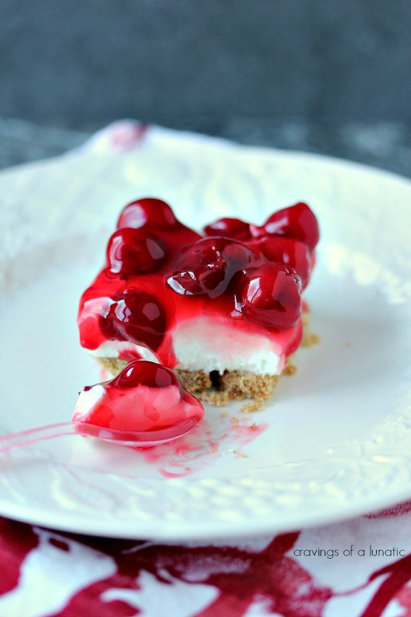 No Bake Cherry Cheesecake Bars served on a white plate with a pink spoon. 