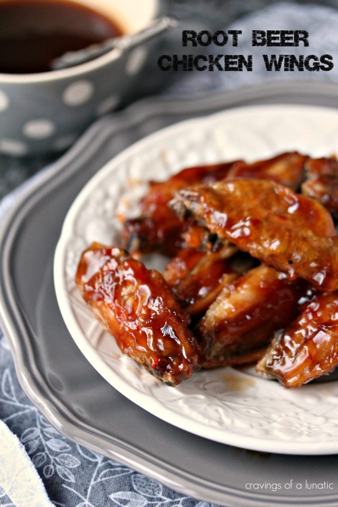 Root Beer Chicken Wings served on a white plate that is stacked on a grey plate. A bowl of the root beer sauce is in the background in a grey bowl with white polka dots. 