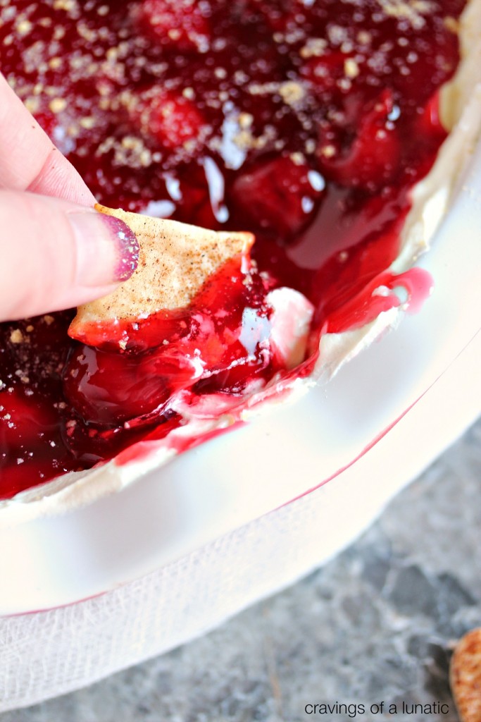 close up image of Cherry Cheesecake Dip in a red and white pie dish being scooped up with Cinnamon Pie Dippers