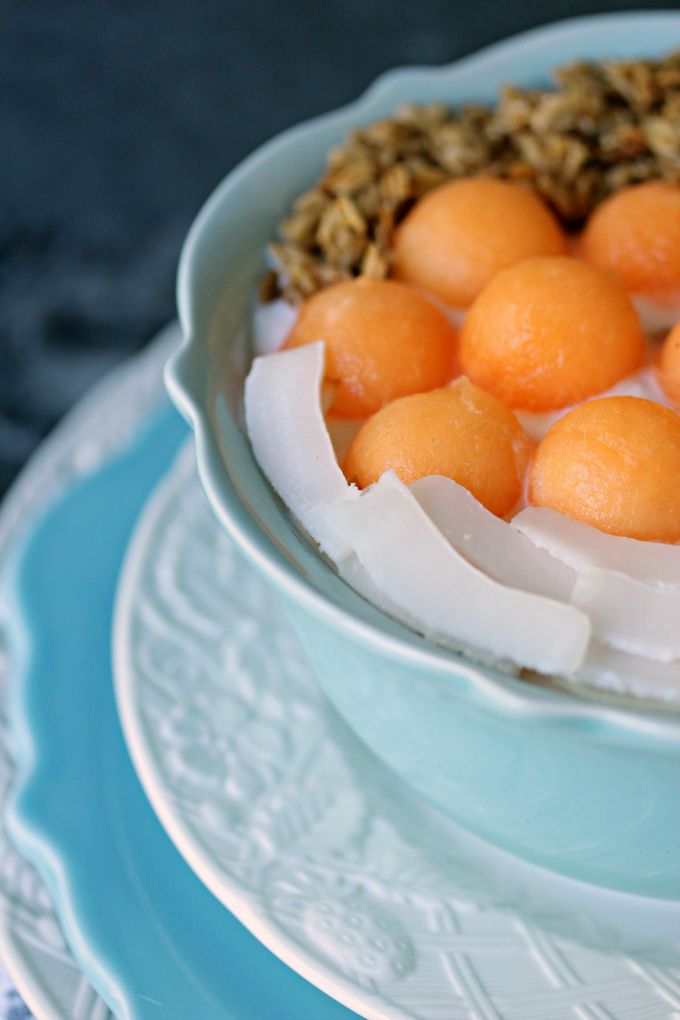 Cantaloupe Breakfast Bowl served in a blue bowl stacked on white and blue plates.