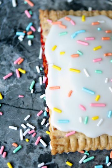 Easy Semi-Homemade Strawberry Pop Tarts on counter with lots of colourful sprinkles scattered around