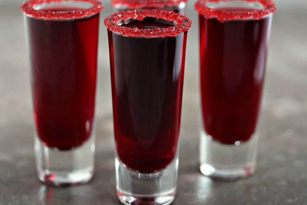 Shot glasses filled with pomegranate "walker blood" sangria on a counter.